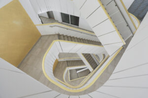 Blick von oben in helles Treppenhaus mit gelben Wandflächen – FLAIR in the City