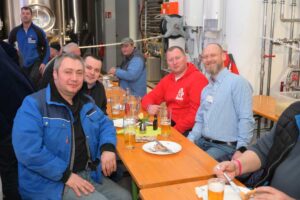 Männer sitzen an langem Tisch mit Bier und Essen bei der Gleichenfeier