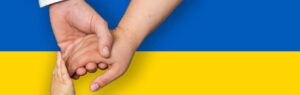 Hände greifen einander vor ukrainischer Flagge – Solidarität mit der Ukraine