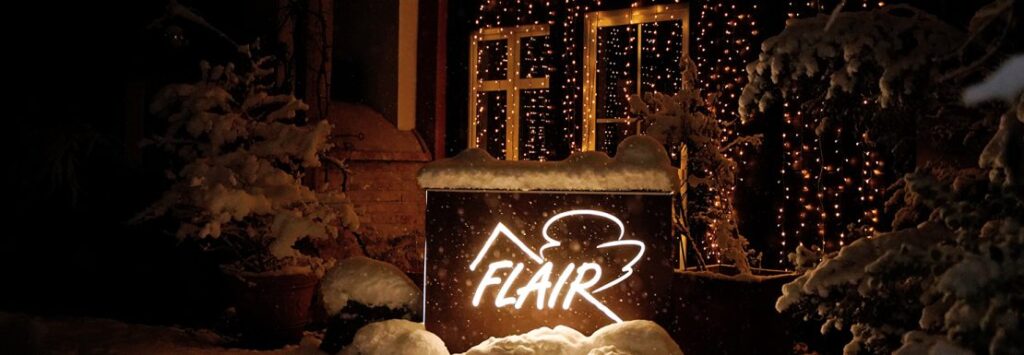 Leuchtendes FLAIR-Logo im Schnee bei abendlicher Winterfeier – meets Friends 2023